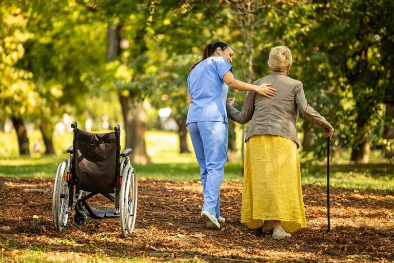 Older adults sitting together with a staff member in a comfortable common room, talking and smiling.